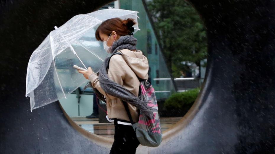 A woman walks in heavy rain and wind as Typhoon Lan approaches Japan's mainland, in Tokyo, Japan, October 22, 2017. REUTERS/Issei Kato - RC15679018F0