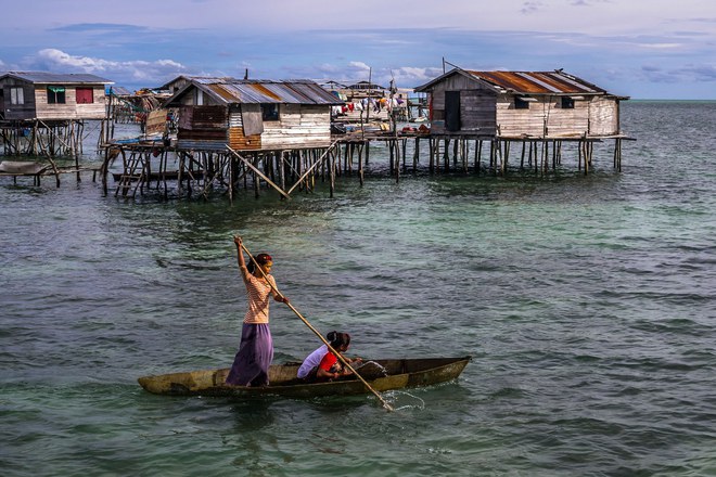 Pic by Claudio Sieber/Caters News - (Pictured: Nusa Tengah village. Boat taxi, the older sister brings her two siblings to a different house. 04/06/2017.) - THESE fascinating images reveal what life is like for the Bajau people - a nomadic tribe who spend their lives on the water. The group have been dubbed sea gypsies thanks to the fact they continue to live a seaborne lifestyle.The striking images - taken by photographer Claudio Sieber - show youngsters out catching fish in long narrow canoes. He took the pictures off the coast of Borneo where the Bajau are able to dive up to 20 metres without the use of modern scuba gear.They even reportedly experience land sickness when they leave the water. SEE CATERS COPY.