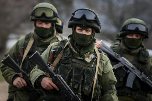 Armed men, believed to be Russian servicemen, march outside an Ukrainian military base in the village of Perevalnoye