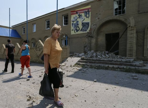 A woman cries as she passes destroyed houses following what locals say was overnight shelling by Ukrainian forces, in Slaviansk