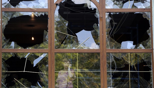 A woman looks out from a damaged window following what locals say was shelling by Ukrainian forces in Donetsk