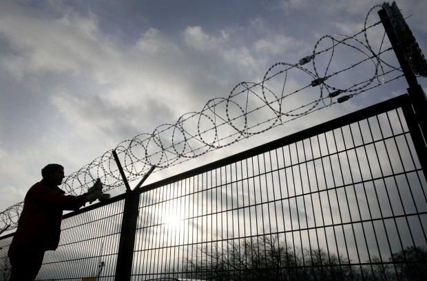 Worker fixes barbed wire on top of panels of a security fence in Heiligendamm