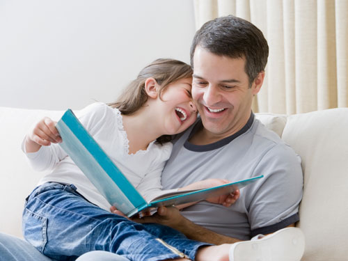 Hispanic father reading book to daughter