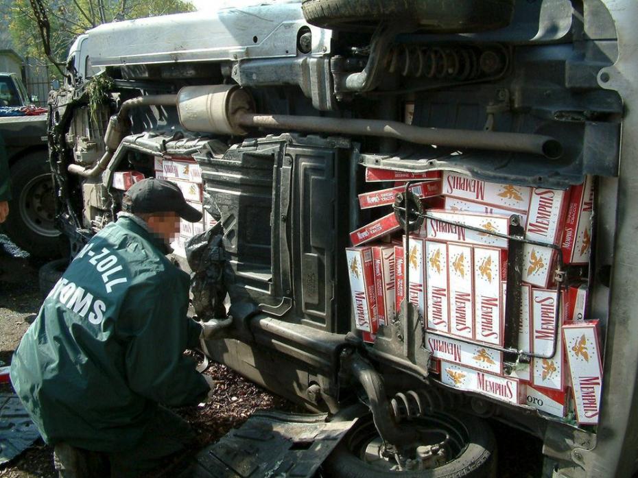 A Hungarian customs officer inspects boxes of cigarettes found in the wreck of a Mercedes minibus