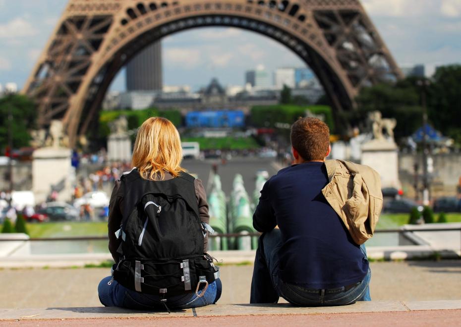 Young tourist couple sitting in front of Eiffel tower in Paris France