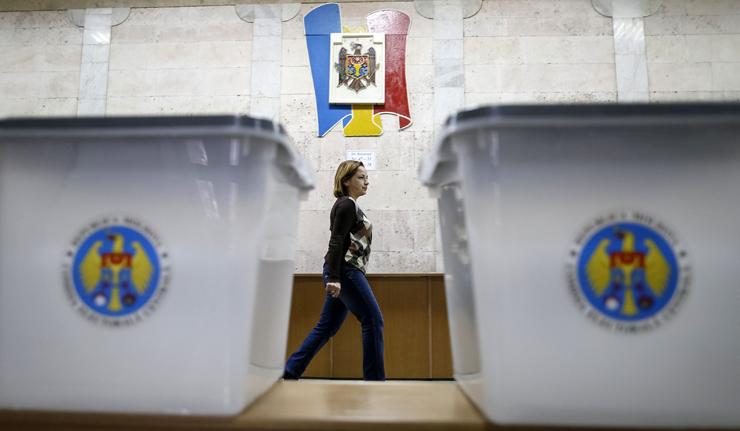 Ballot boxes are seen as a member of a local electoral commission passes by at a polling station in Chisinau