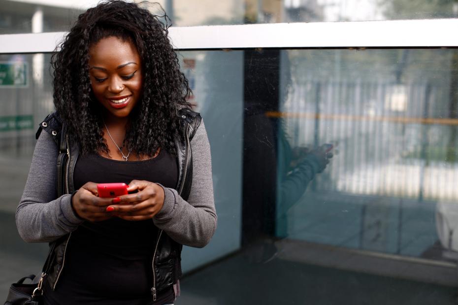 Young African woman sending an sms on her mobile