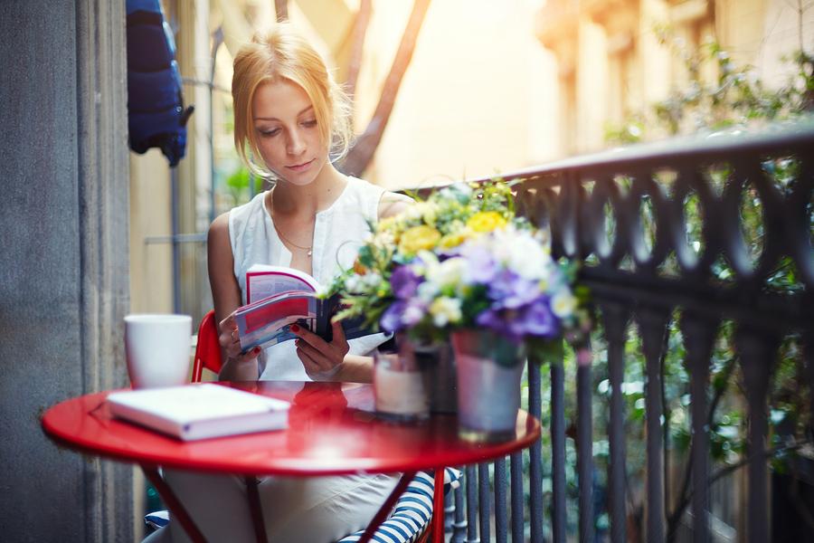 Attractive young girl reading book while drinking coffee at sunn