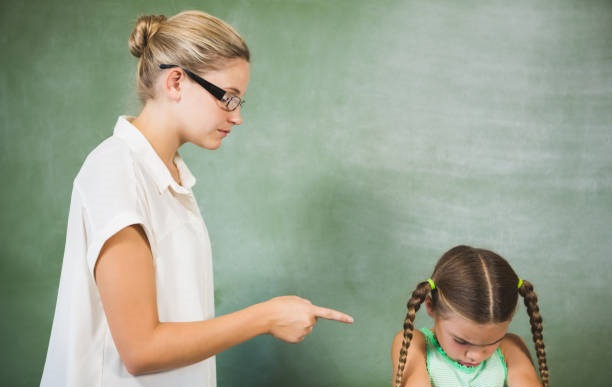 Female teacher shouting at girl in classroom at school