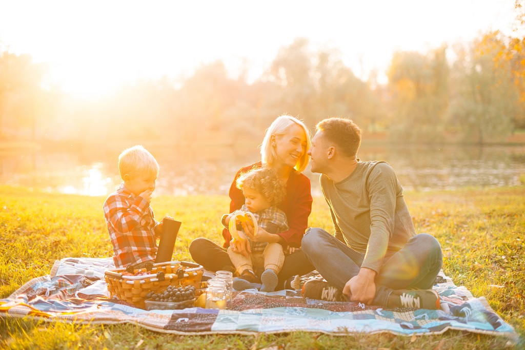 Beautiful and happy young family with kids having picnic time to