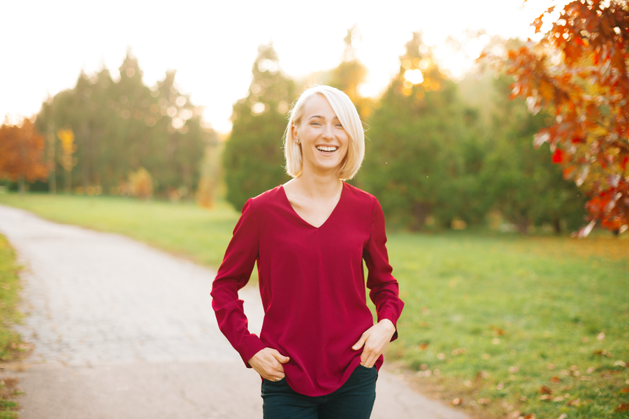 Cheerful young blonde woman, walking in autumn park, smling and