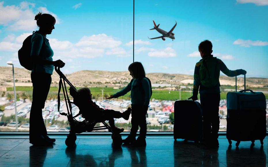 mother with kids and luggage looking at planes in airport