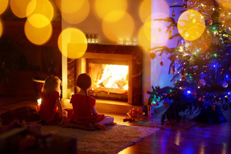 Happy little girls sitting by a fireplace on Christmas eve