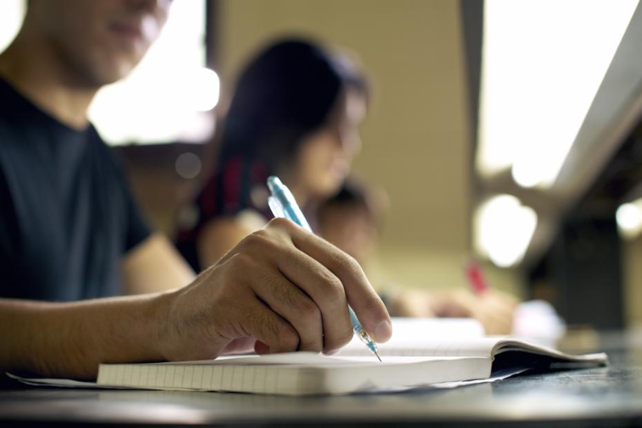 young man doing homework and studying in college library