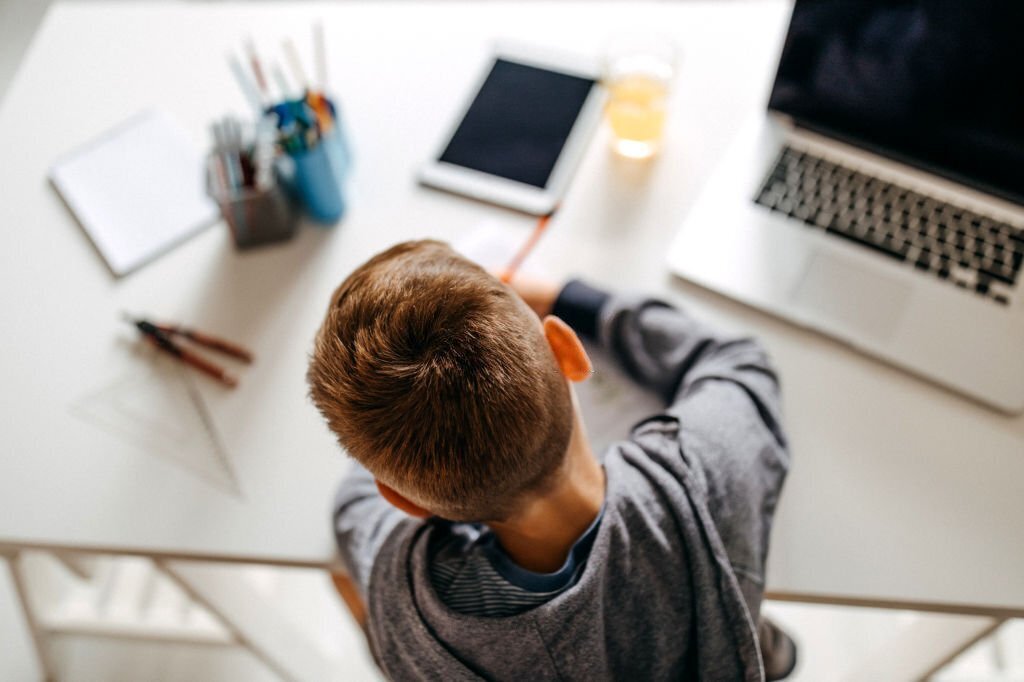 Young boy sitting in his room and doing homework