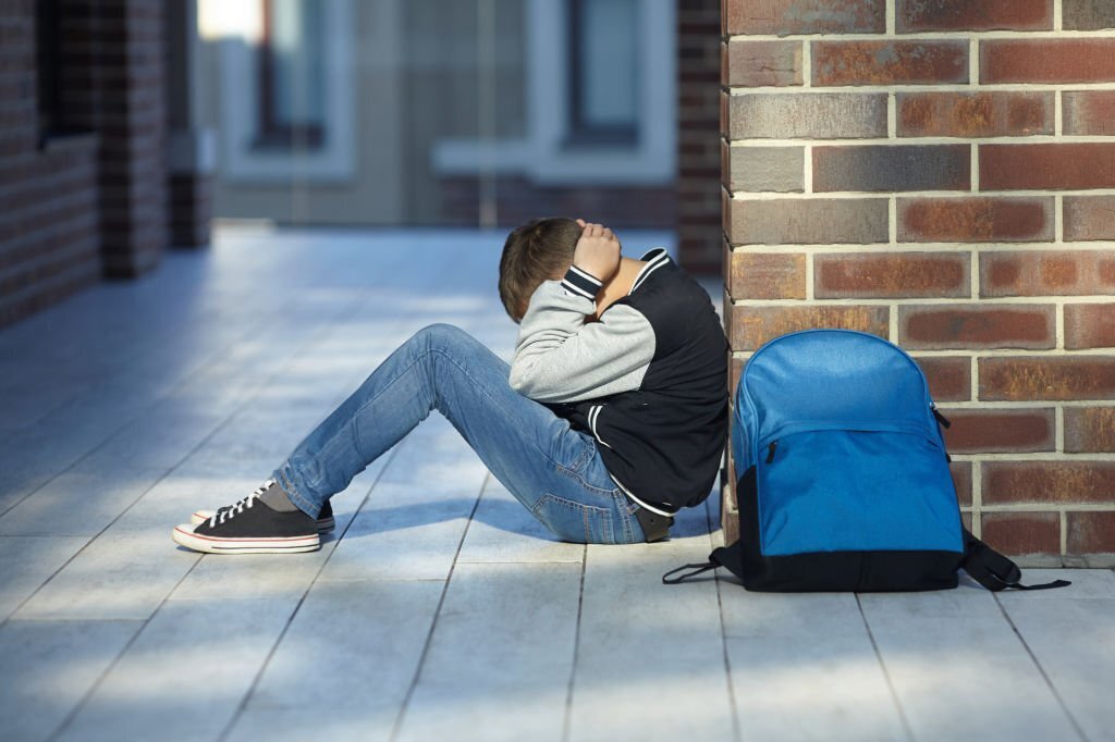 schoolboy crying in the hallway of the school, negative emotion