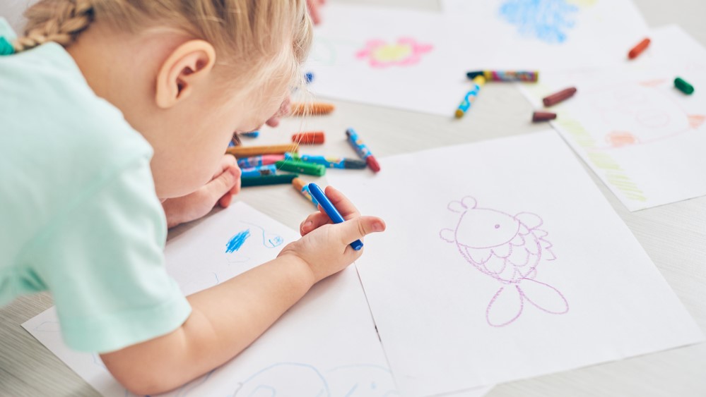 Little baby girl drawing pictures with pencils on the floor