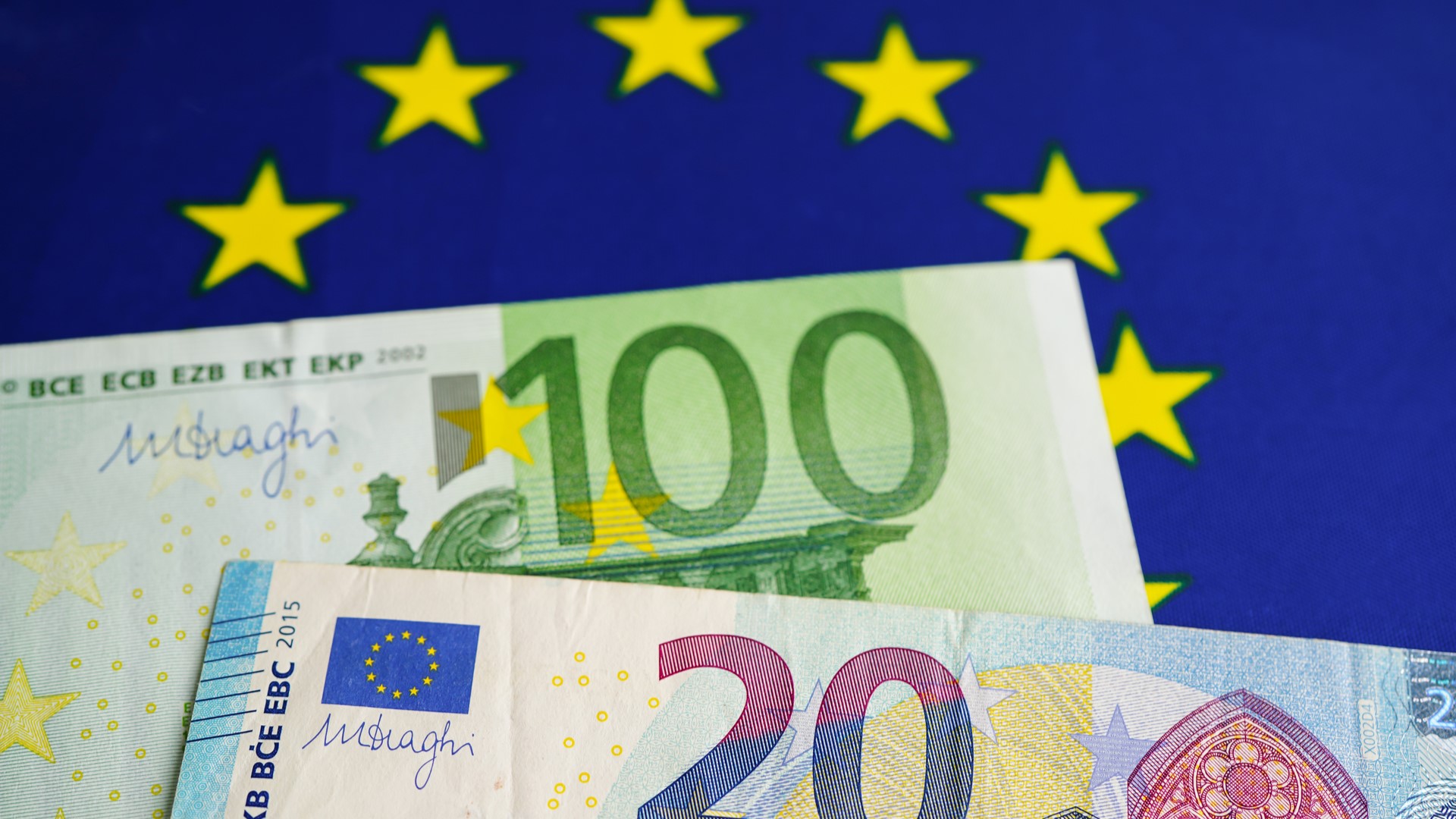 Euro banknotes money on EU flag, economy trade in europe concept.